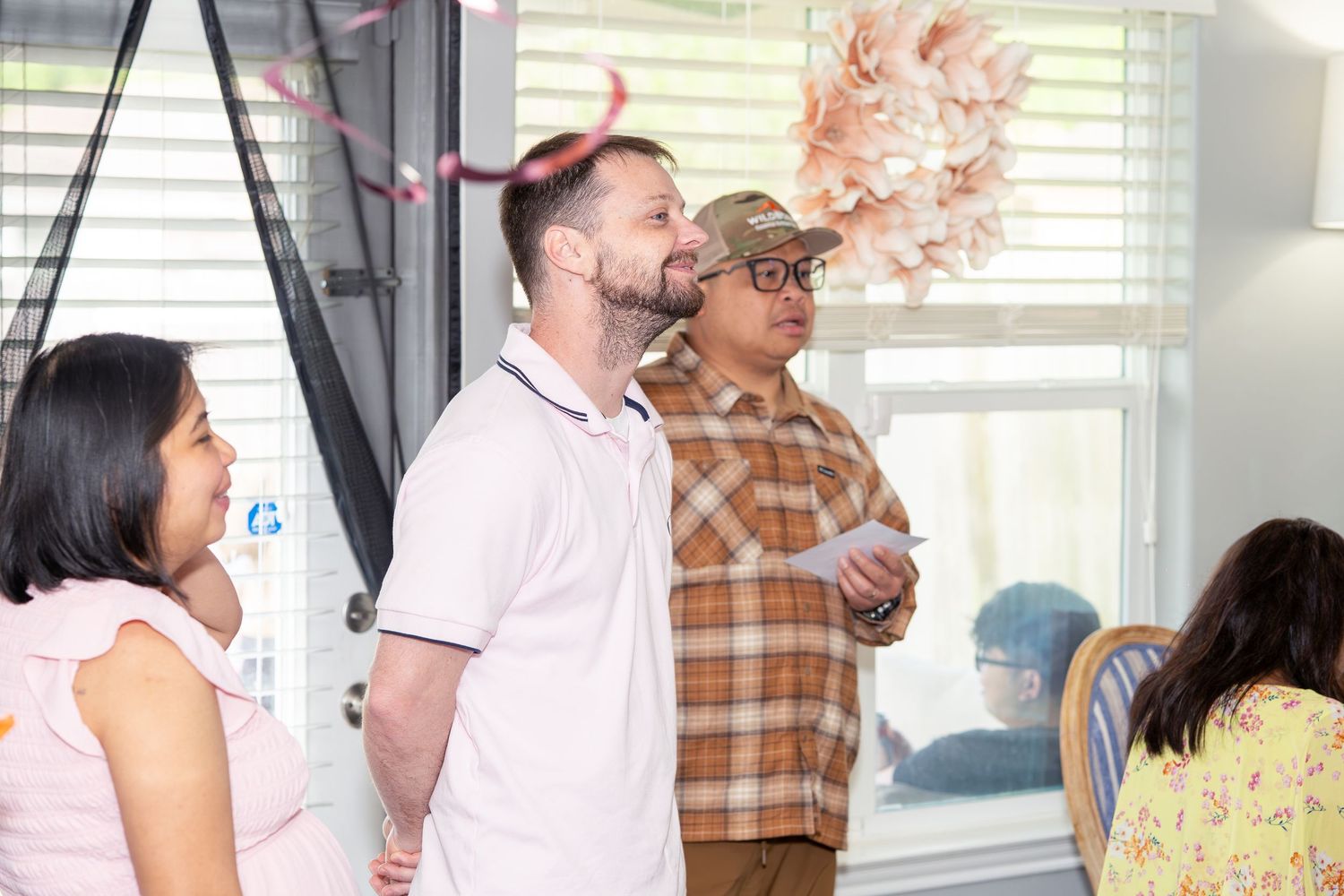 Group of people standing indoors at a celebration with colorful confetti falling around them.