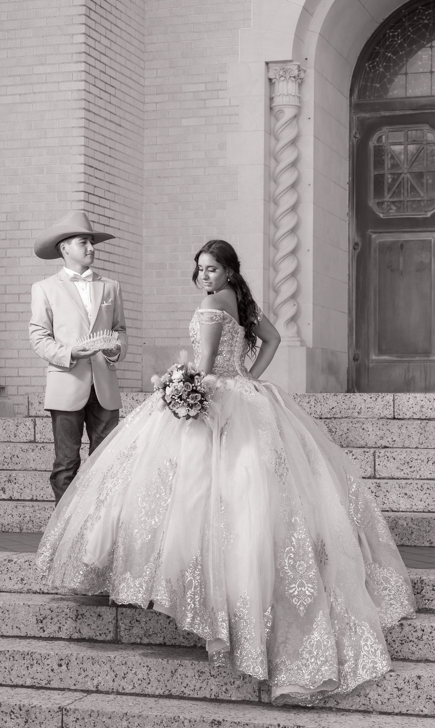 Black and white sequence of a bride in a lace ballgown twirling on stone steps of a historic building.