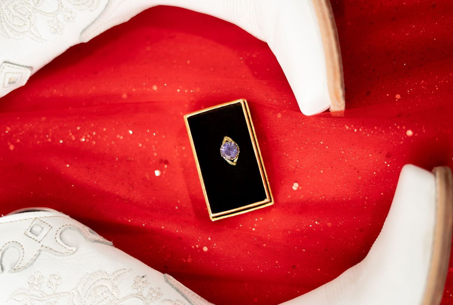 A small black and gold pin displayed on a vibrant red fabric background with white accents.