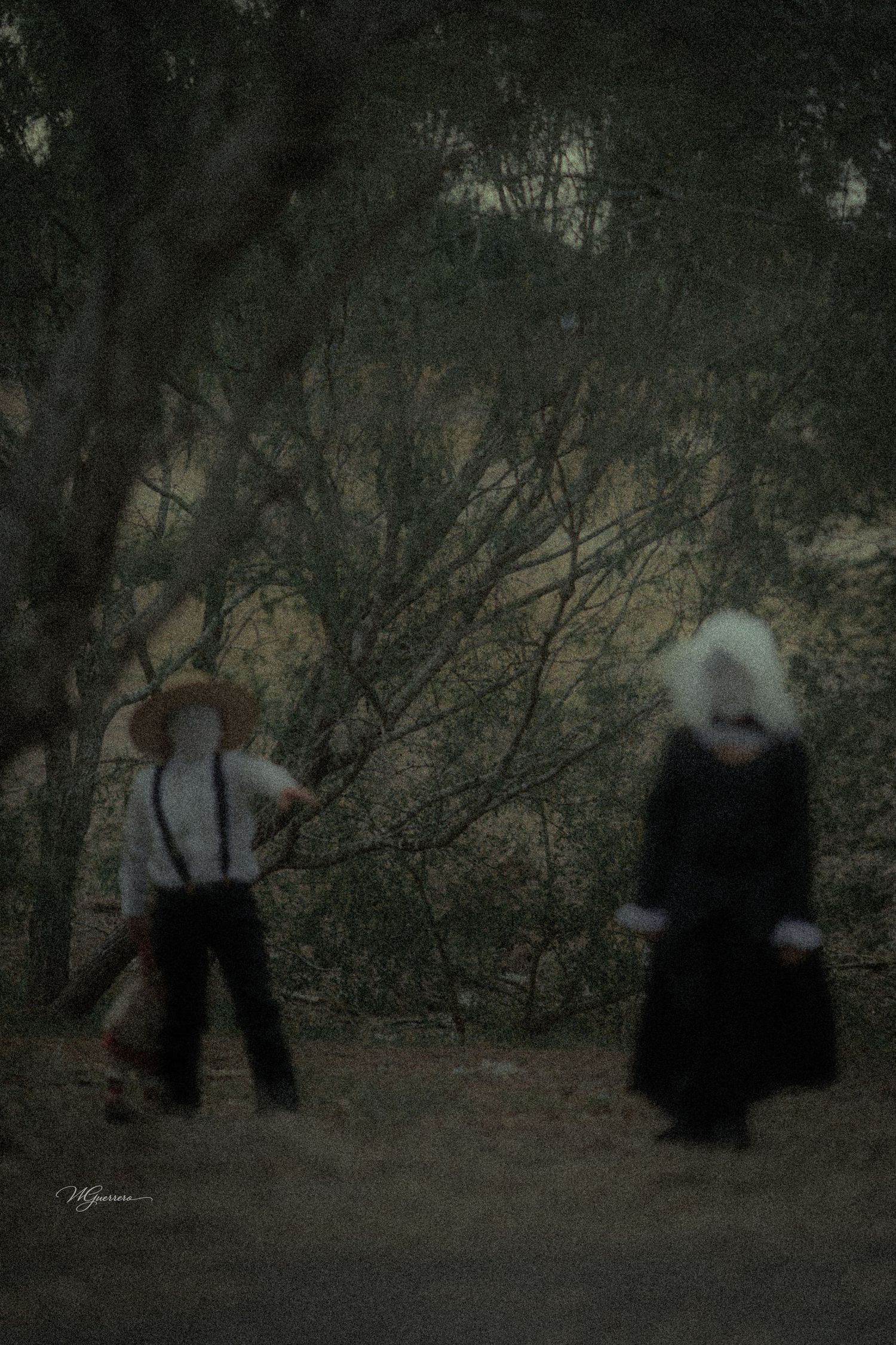 Two blurred figures in traditional Amish attire walk through a dark wooded area, one holding a rake.