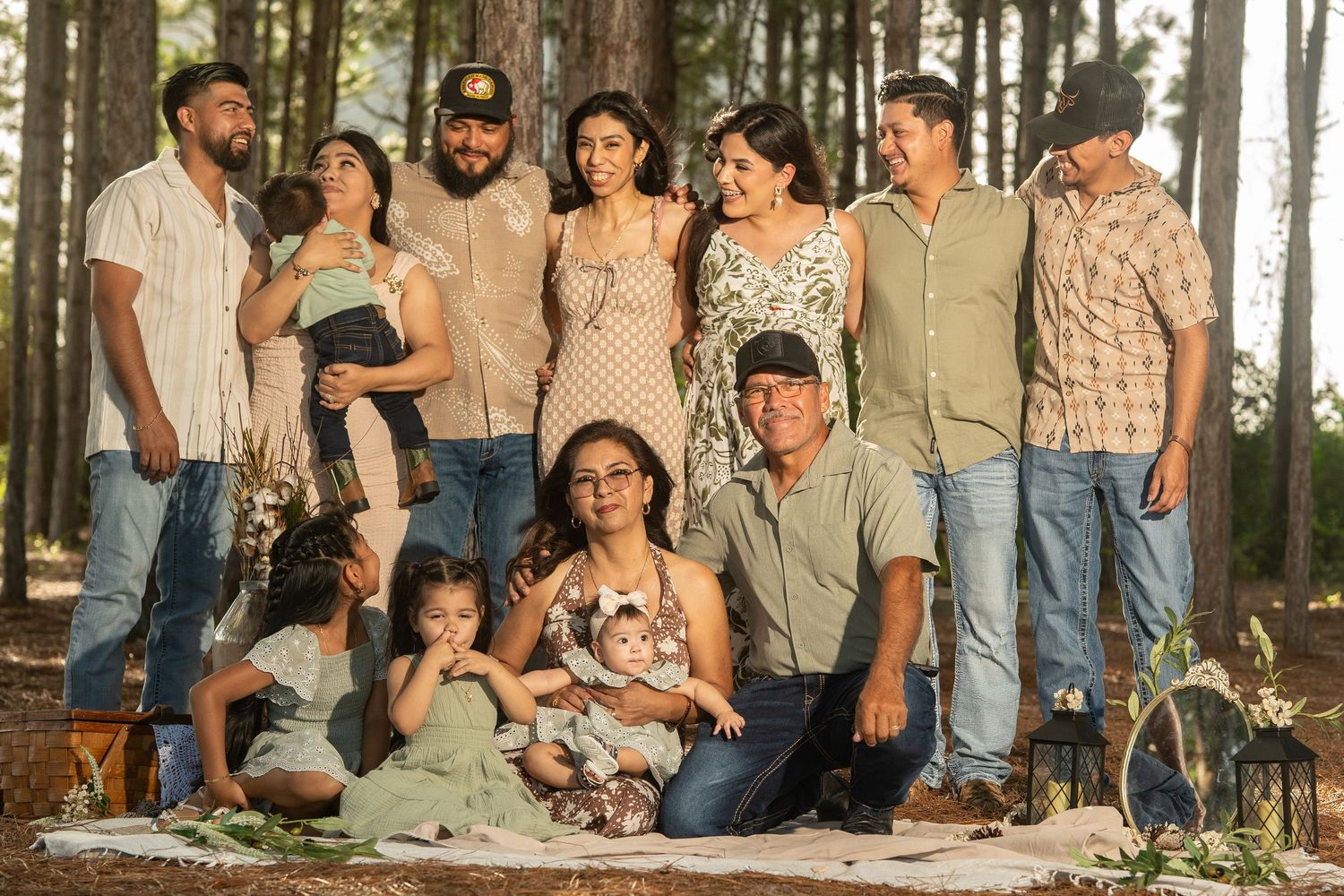 Large Hispanic family posing together for a portrait in a pine forest during golden hour.