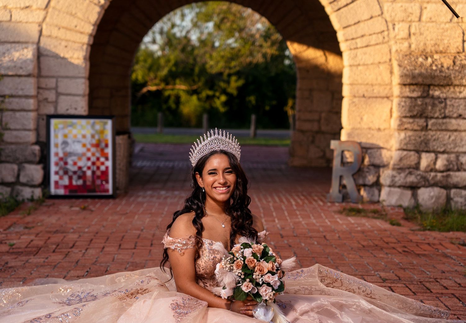 A person in a white floral gown poses on brick steps at sunset during a wedding photo session.