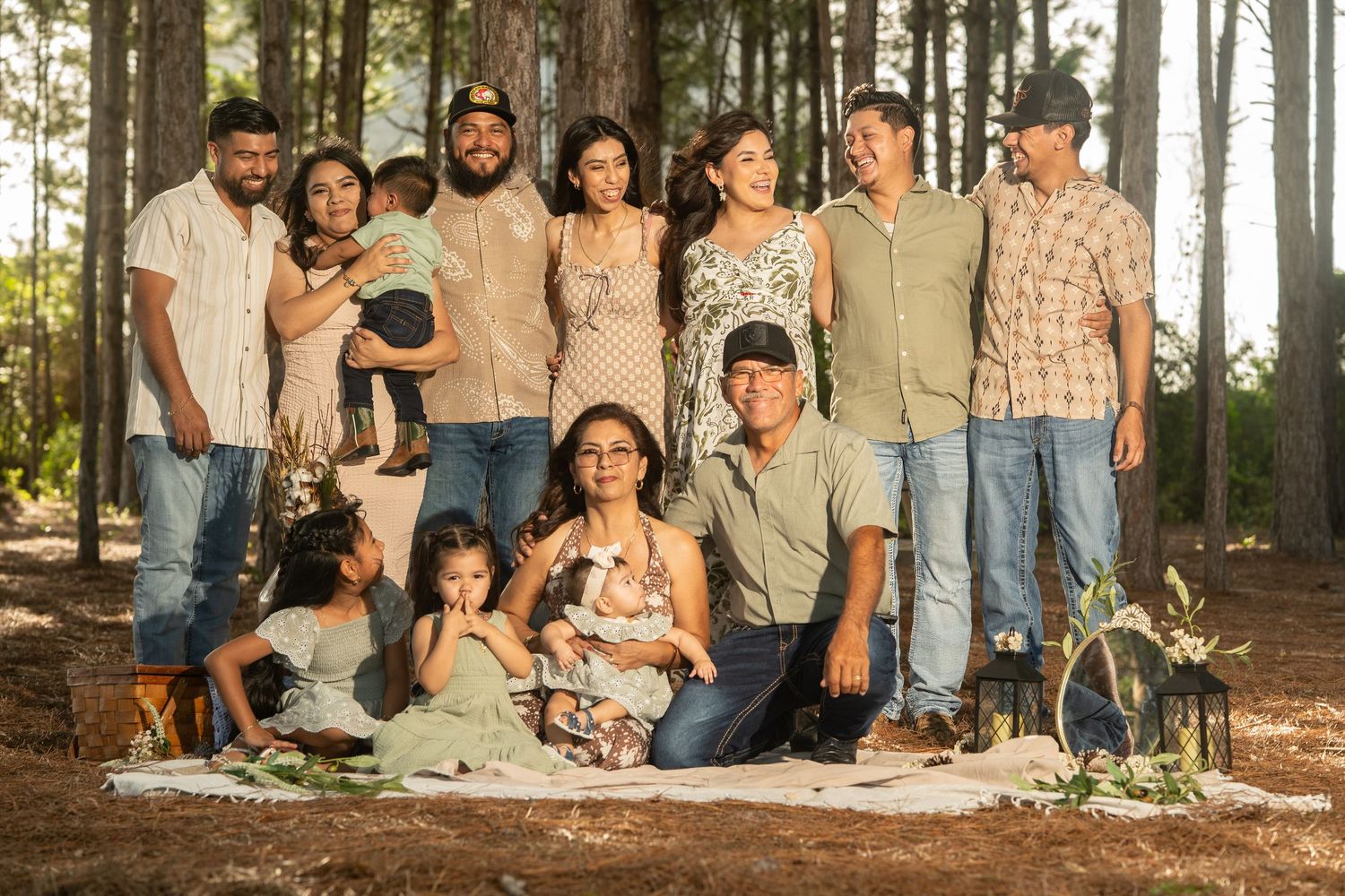 Large Hispanic family posing together outdoors among pine trees for a professional portrait photo session.