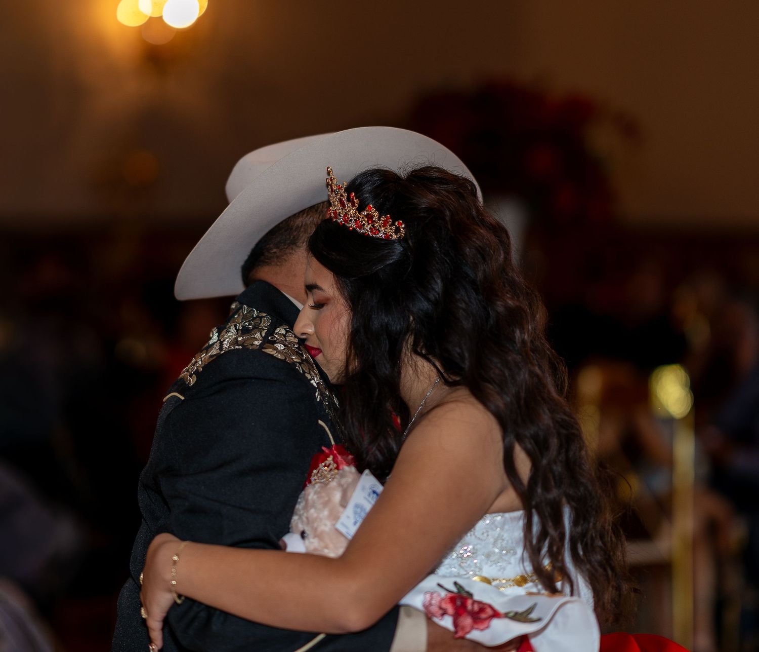 Couples dancing together in a dimly lit room with warm lighting during a romantic celebration event.