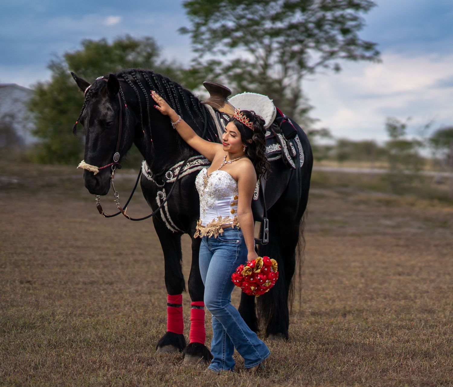 A black horse and rider pose in a rustic field setting during a photo session.