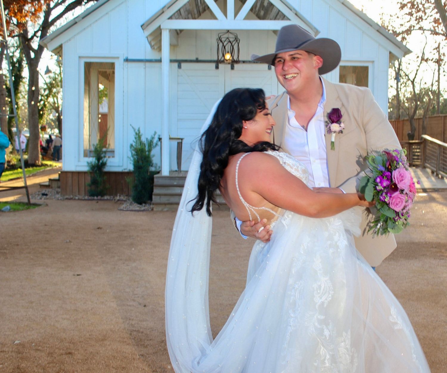 A romantic outdoor wedding ceremony shows the joyful couple embracing in a beautiful garden setting.