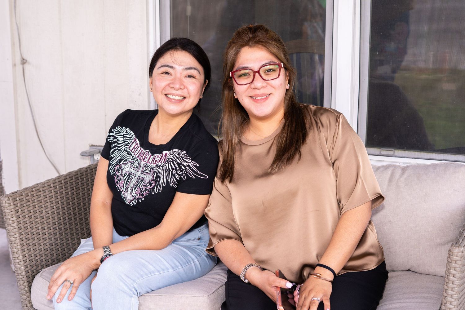 Two smiling women sitting together on a couch posing for a photo.