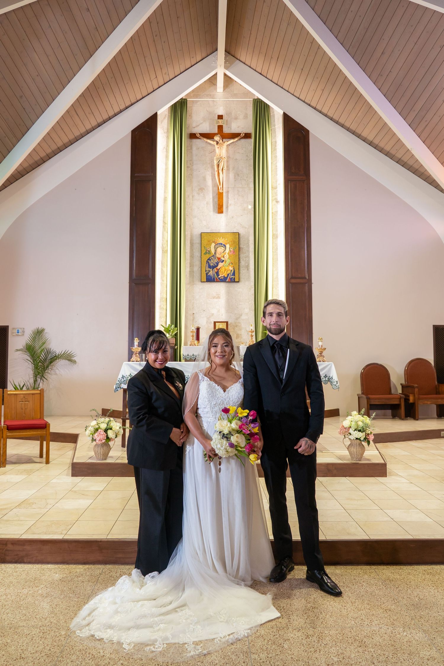 A wedding ceremony inside a church with vaulted wooden ceilings and religious artwork.