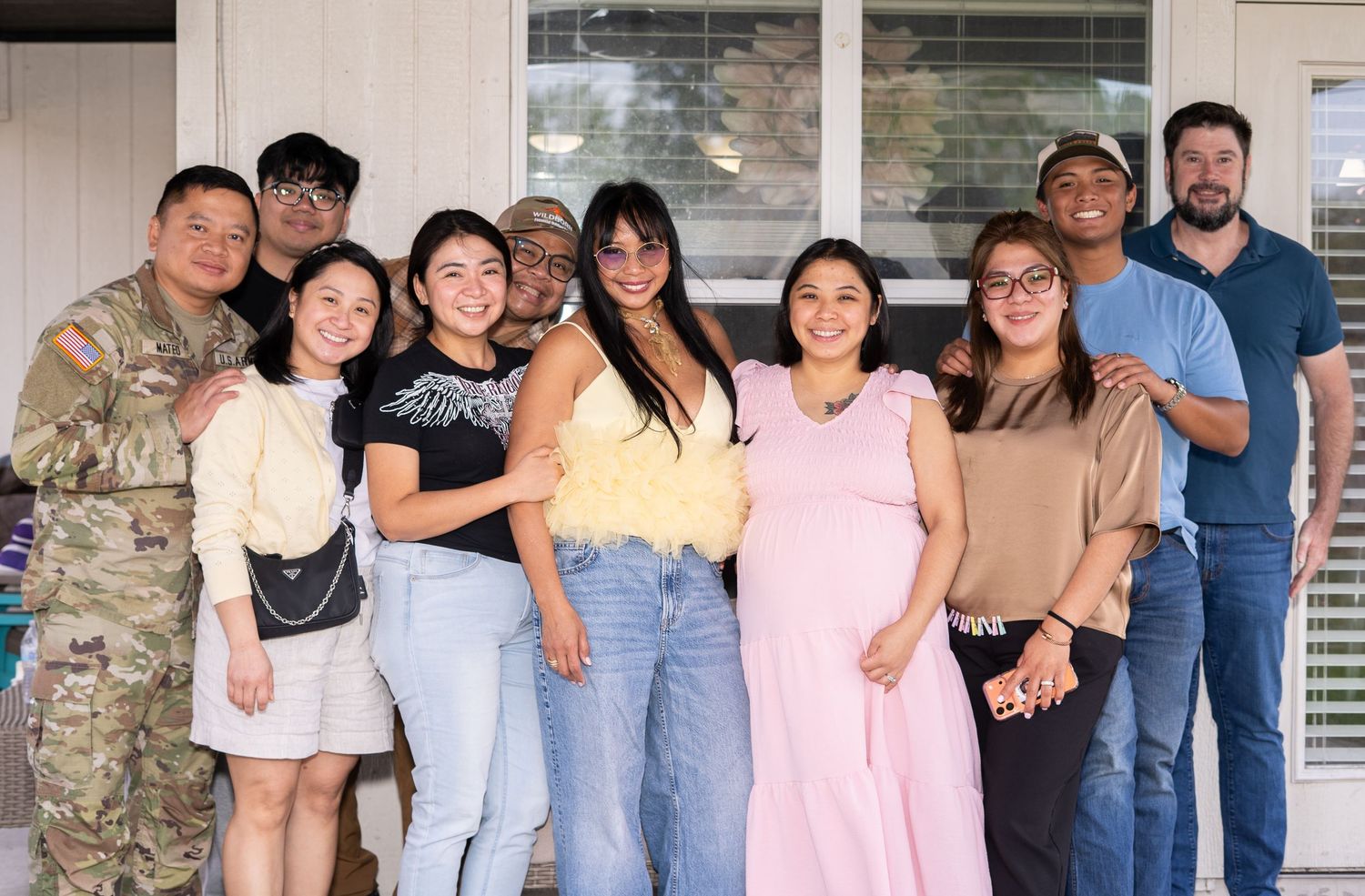 Large family group of ten adults posing together outside a home during a celebration.