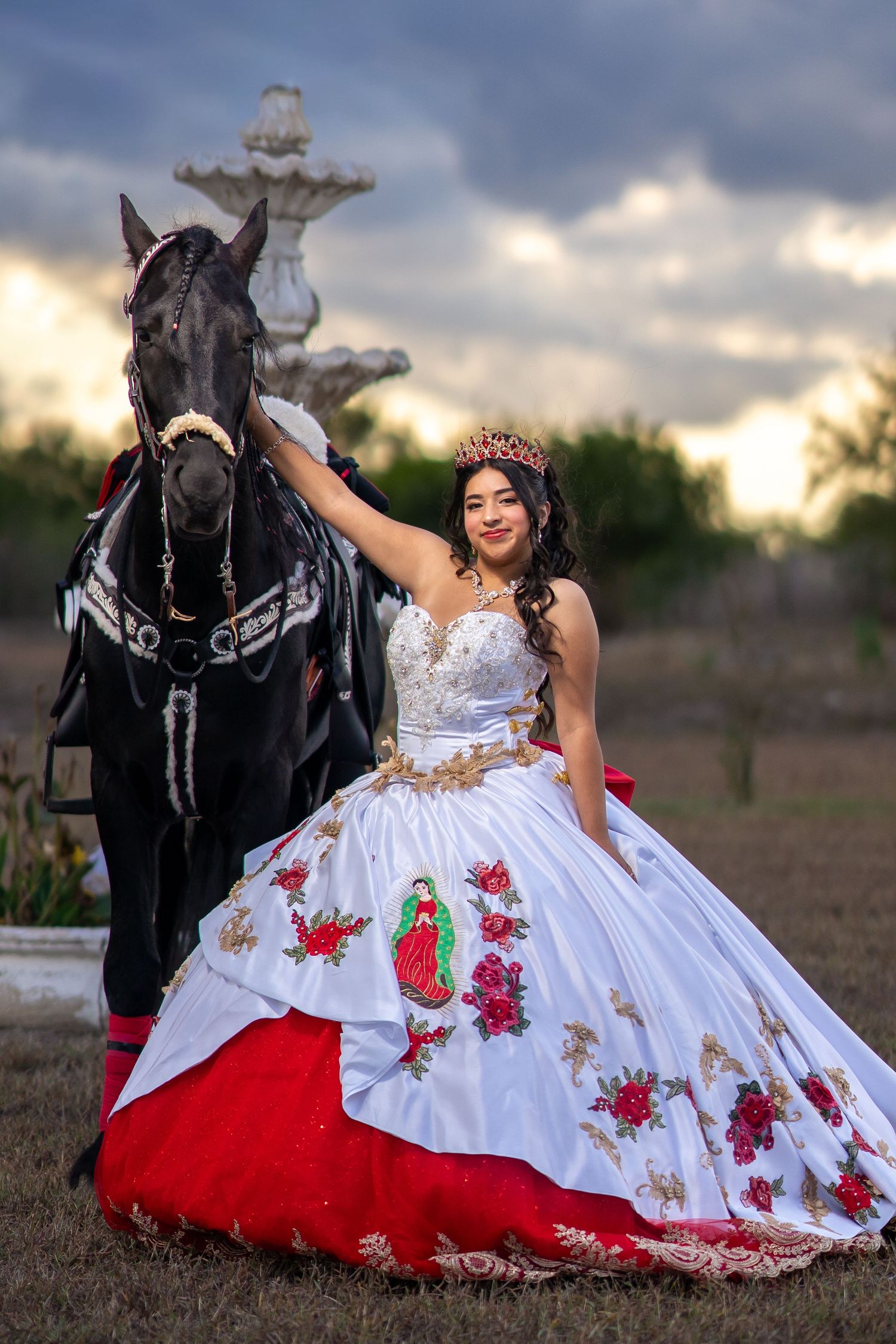 Beautiful ball gown with red rose details and white fabric spread elegantly across outdoor terrain.