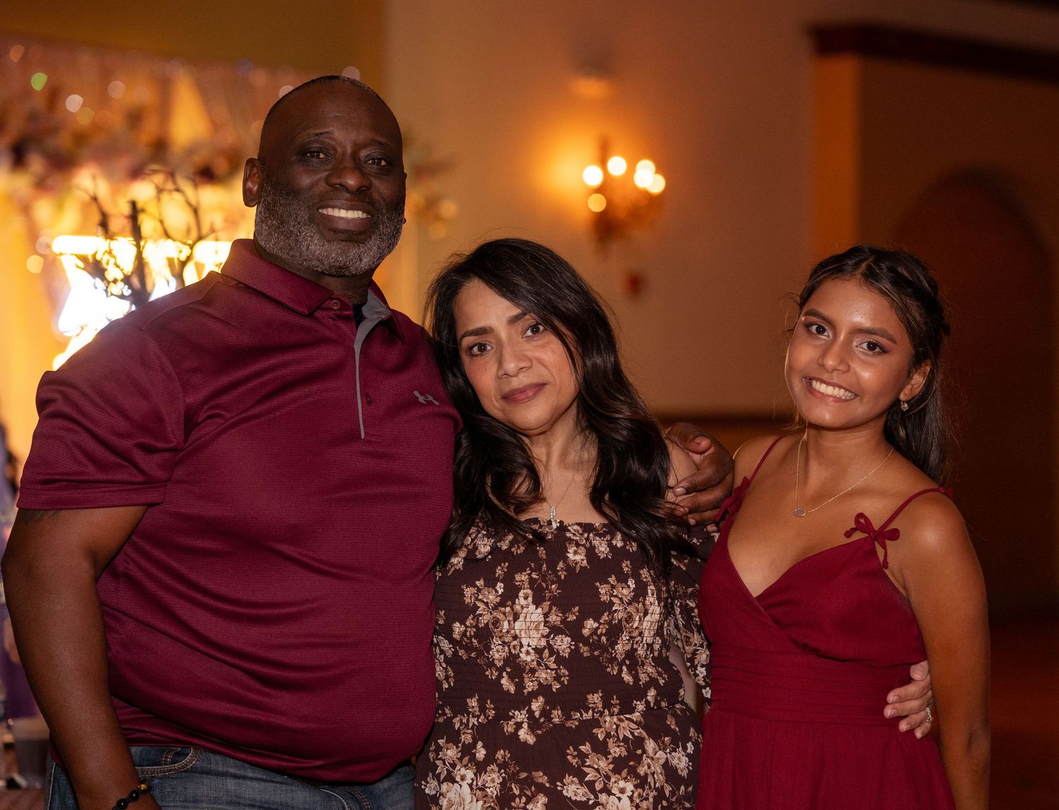 Three people pose together smiling at an elegant quinceañera celebration event.