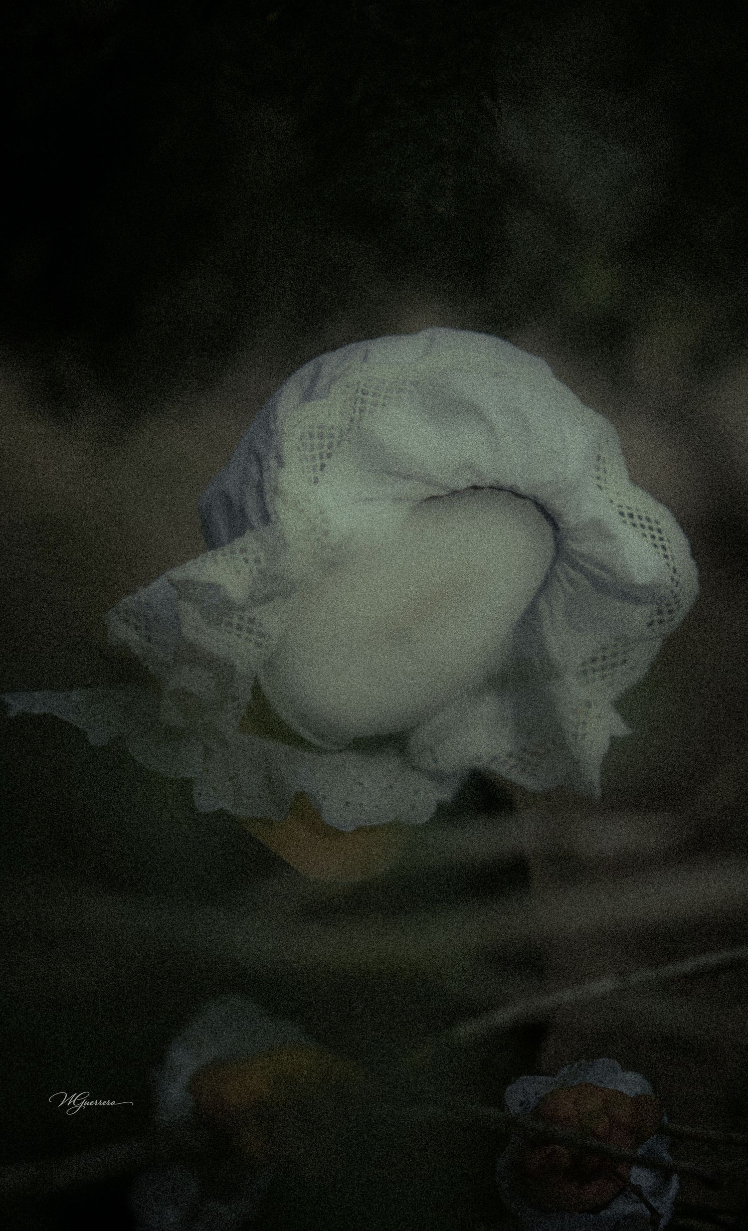 A white lace bonnet rests delicately on a dark, moody background in a vintage-style fine art photograph.