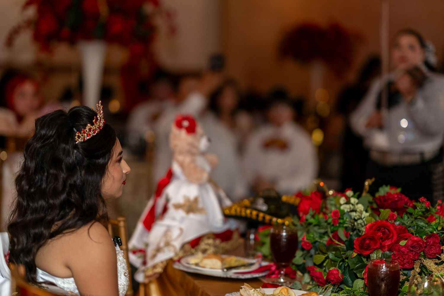 A festive banquet table decorated with red flowers and place settings for a traditional Mexican celebration.