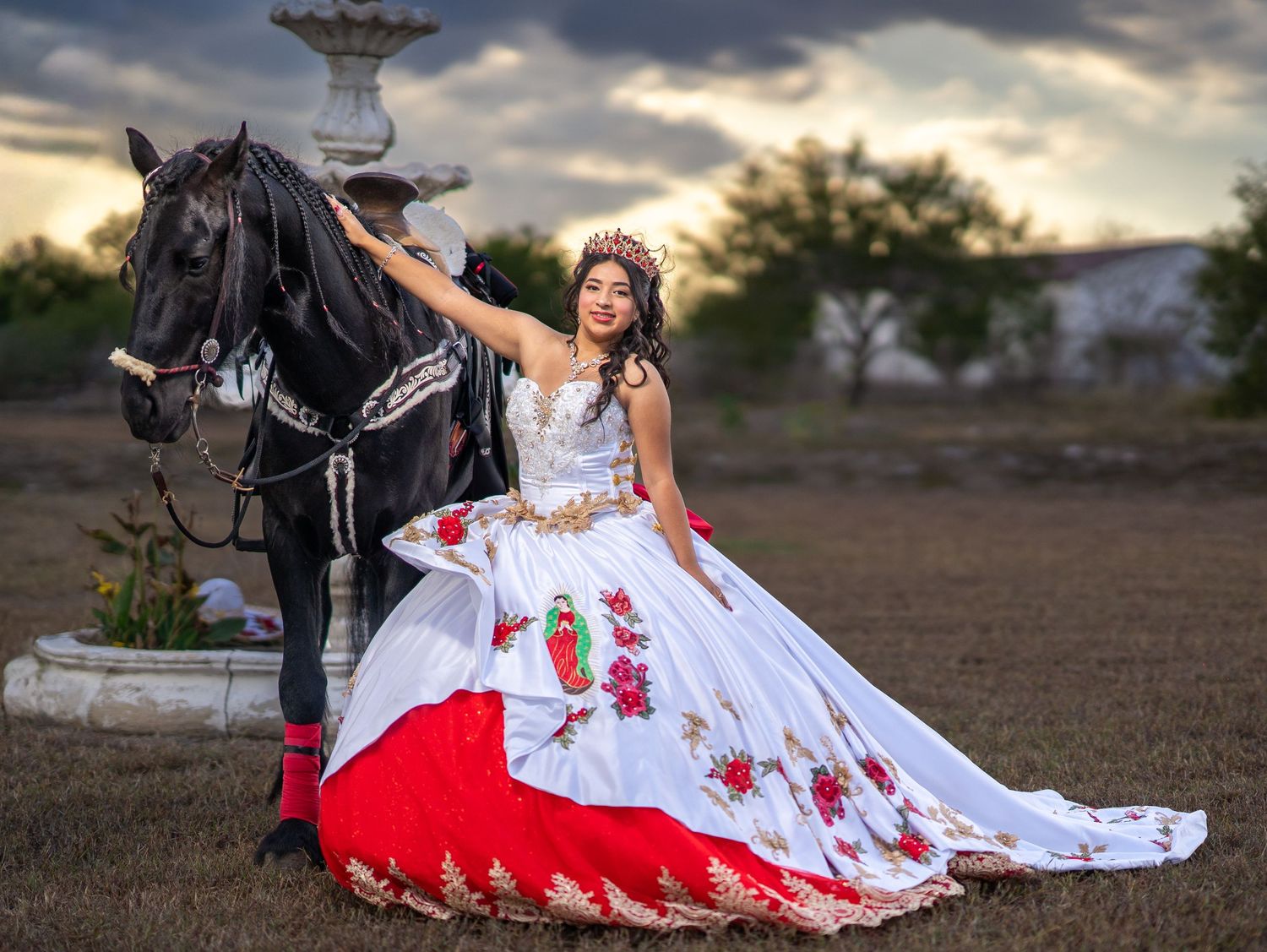 Dramatic outdoor portrait session with a flowing white and red dress against moody storm clouds at sunset.