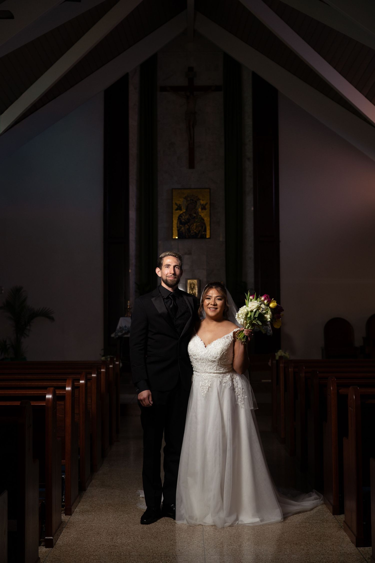 Dramatic lighting captures a wedding ceremony moment in a church sanctuary.