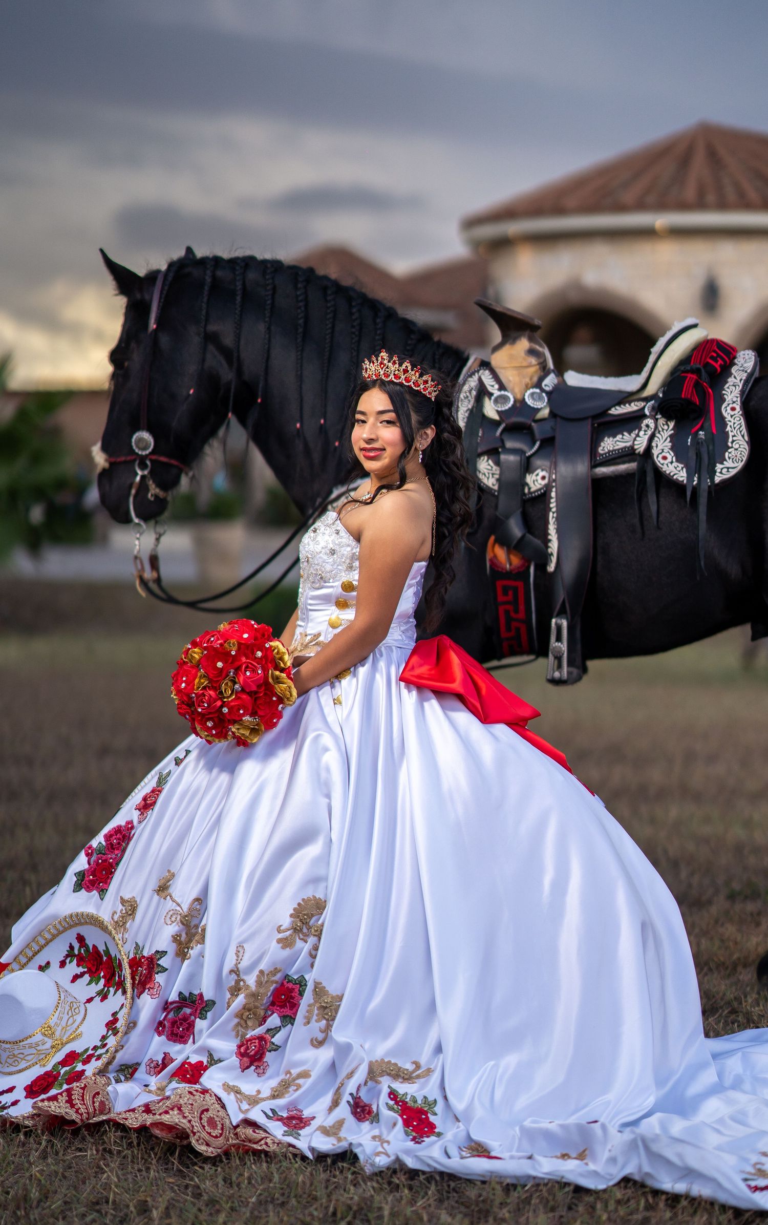A formal white dress with red accents is showcased next to a black horse in an outdoor setting.