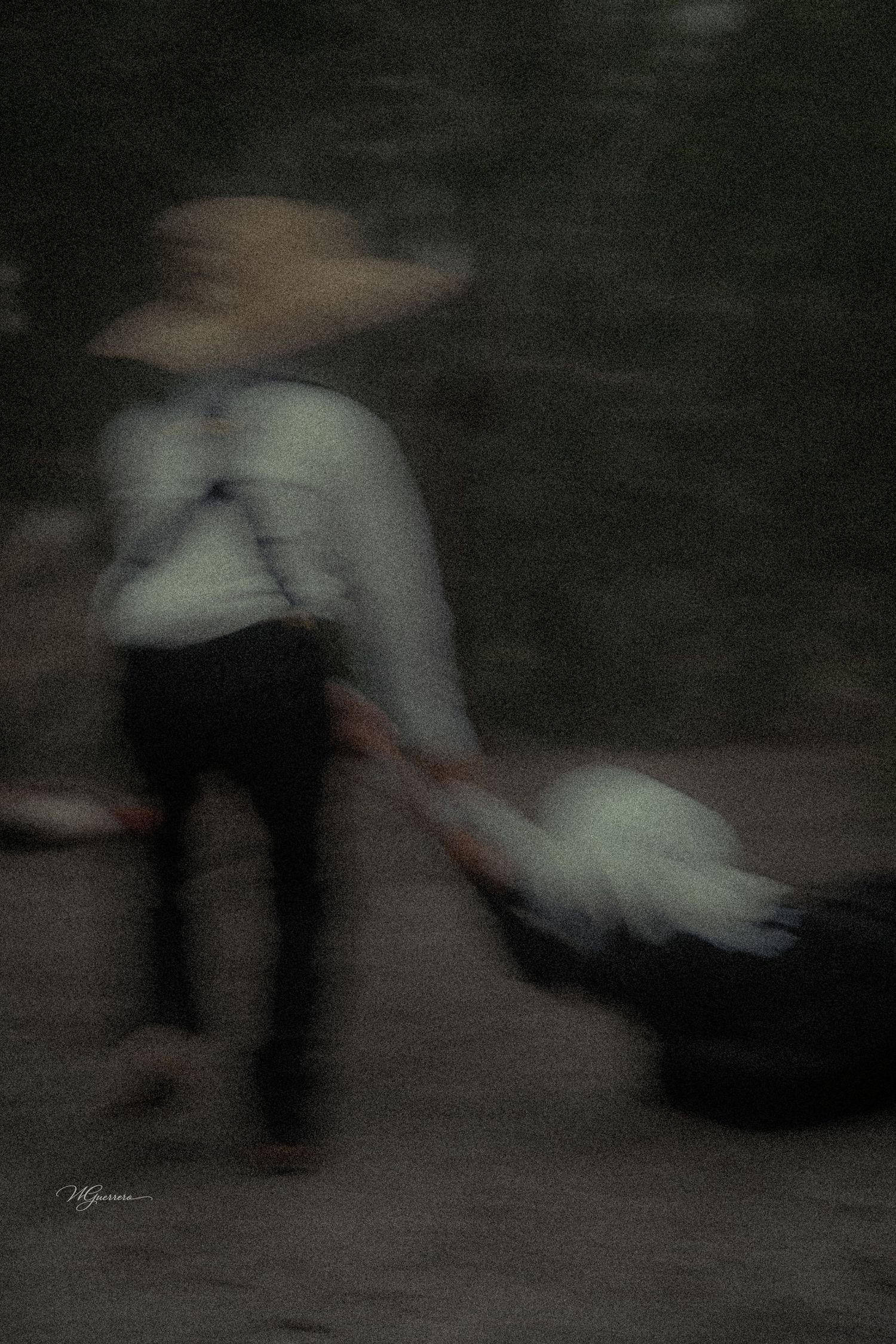 Blurred motion photo of a person in a straw hat pulling a cart on a dark street.