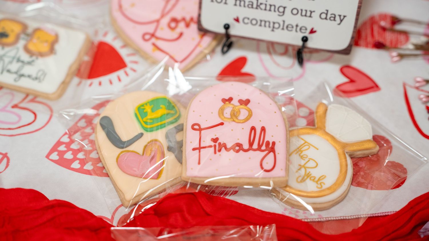 Decorated wedding cookies in clear bags featuring pink frosting with “Finally” text, rings, and colorful celebration designs.