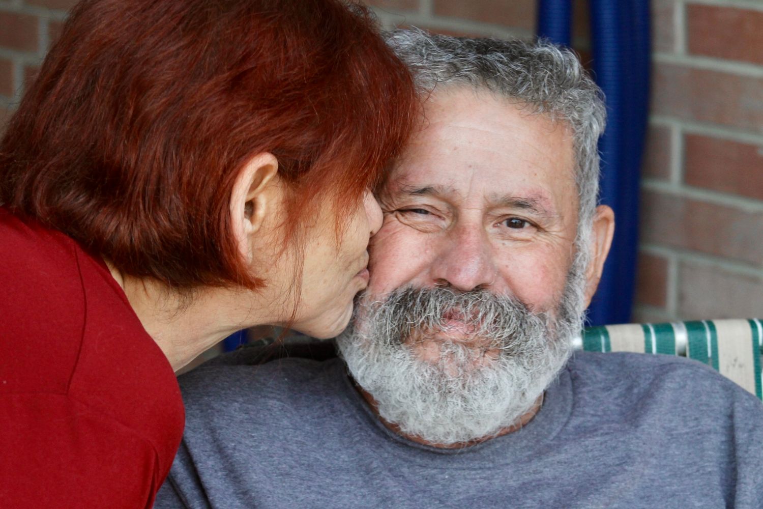 A tender moment shared between a couple with one person in red and one wearing grey.
