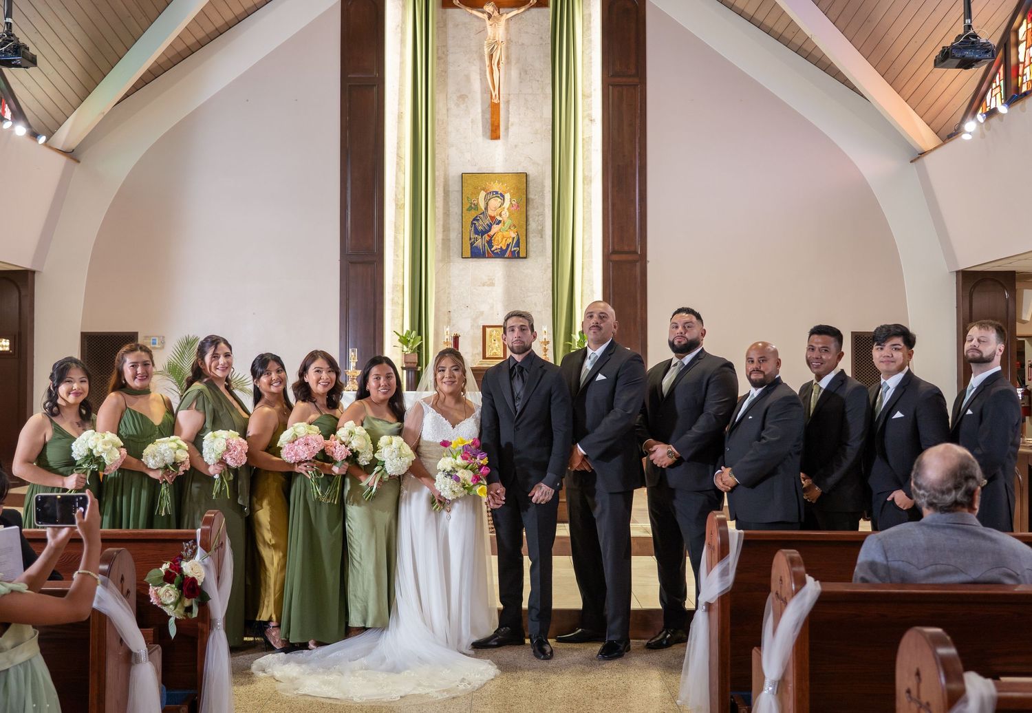 Wedding party poses with bride and groom at church altar after ceremony.