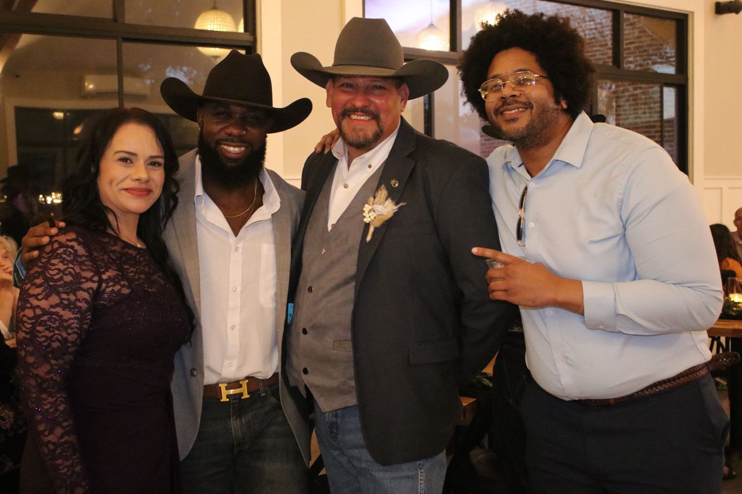 Four people pose together at an event, with two wearing cowboy hats and western attire.