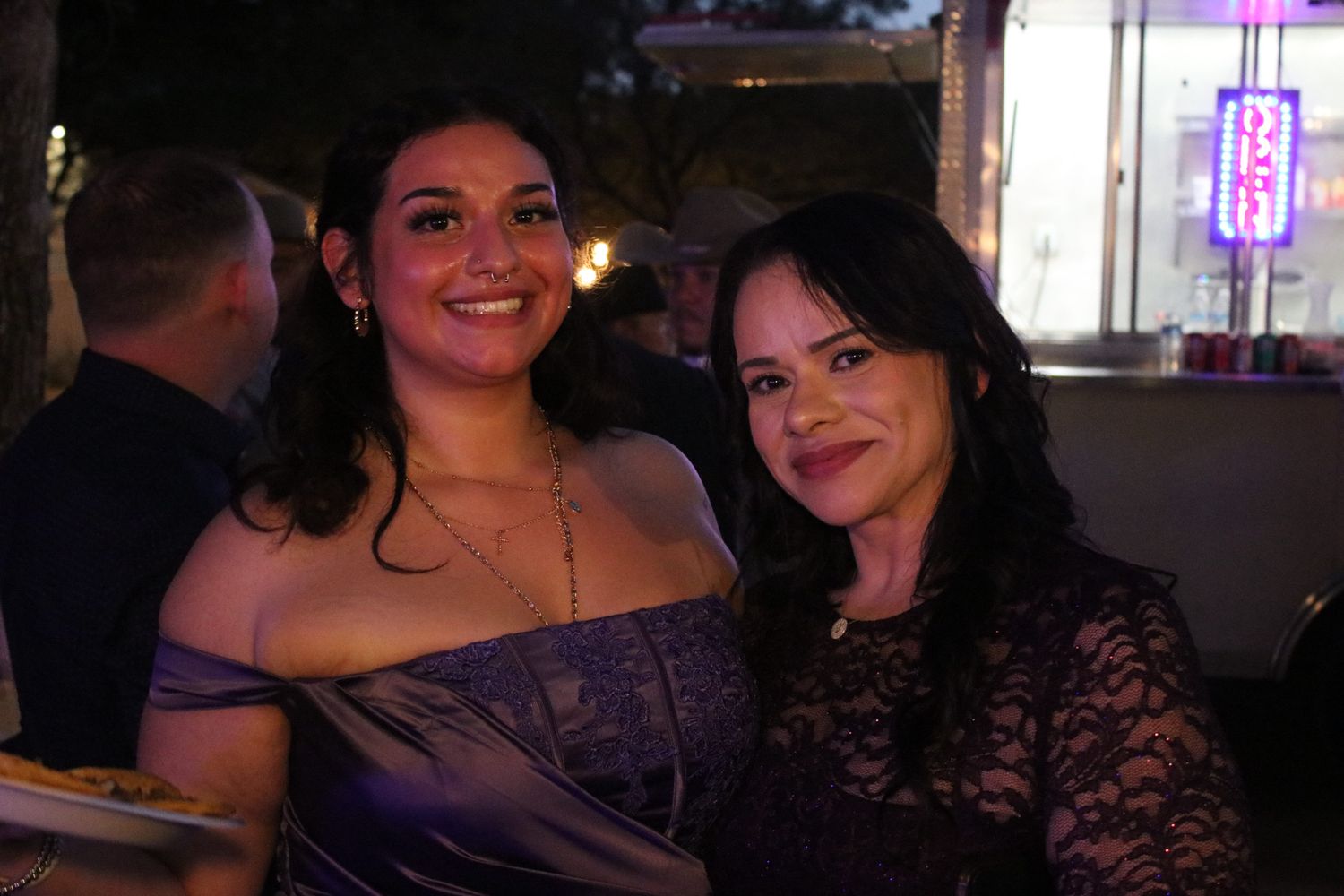 Two guests enjoying an evening celebration with string lights in the background.