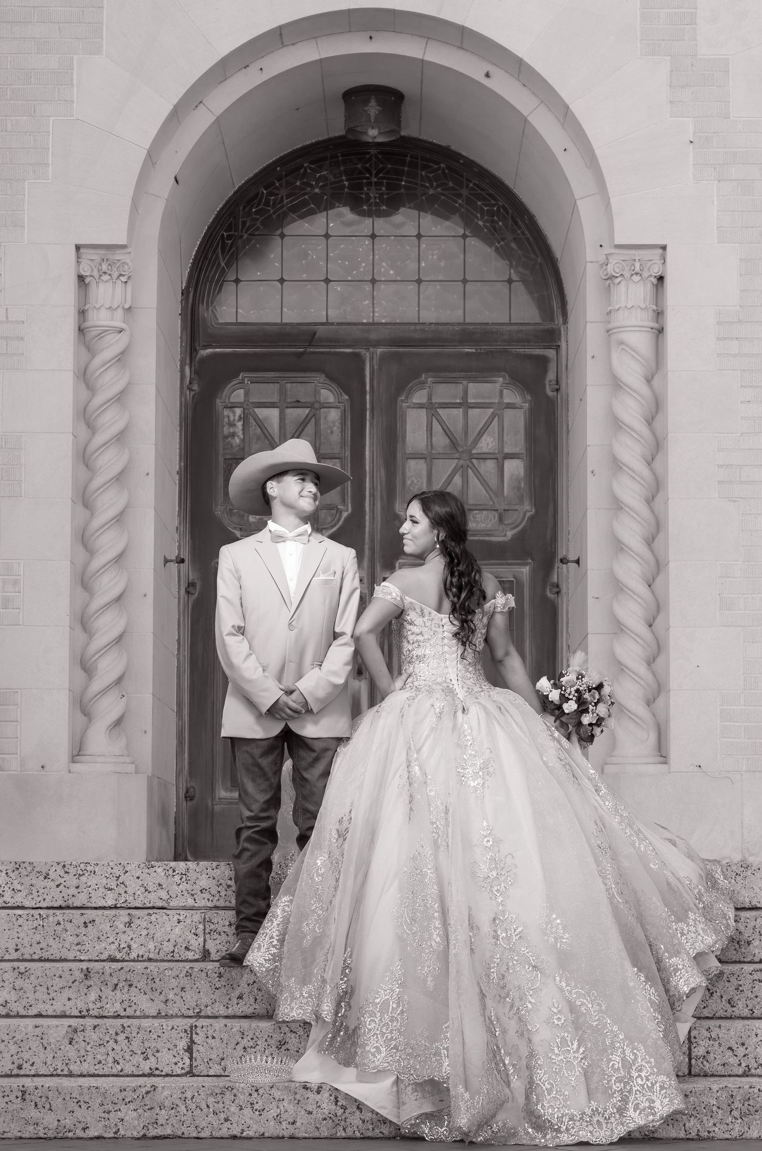 A couple in wedding attire poses in front of ornate arched doorways in a black and white photo series.