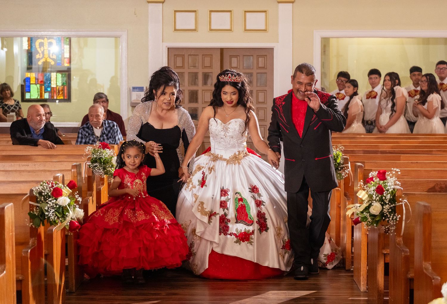 A church pew panorama with wedding guests and floral decorations during a ceremony.