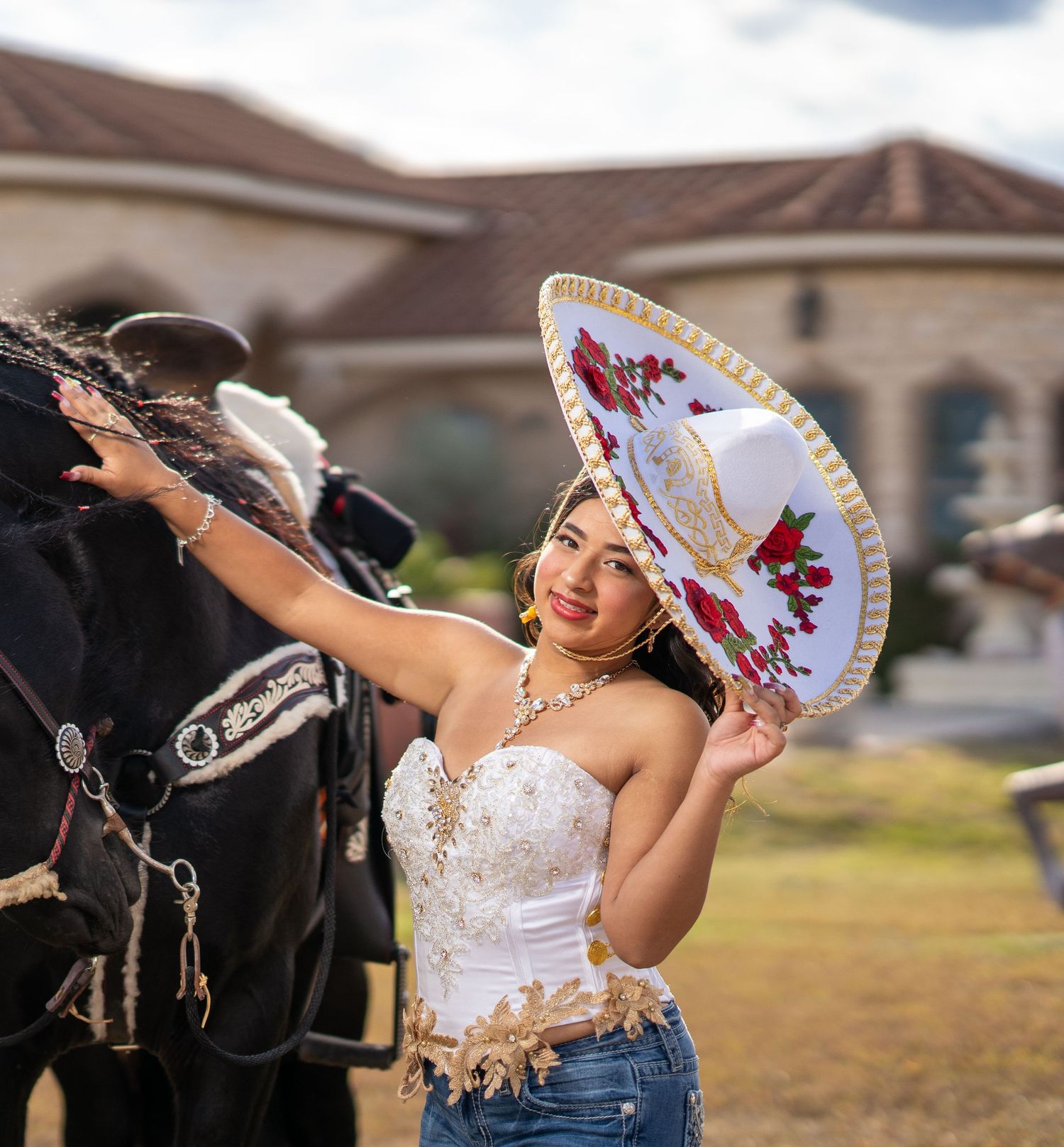 Quinceañera photoshoot featuring an elegant white and red embroidered dress with a decorative fan against a sunset backdrop.