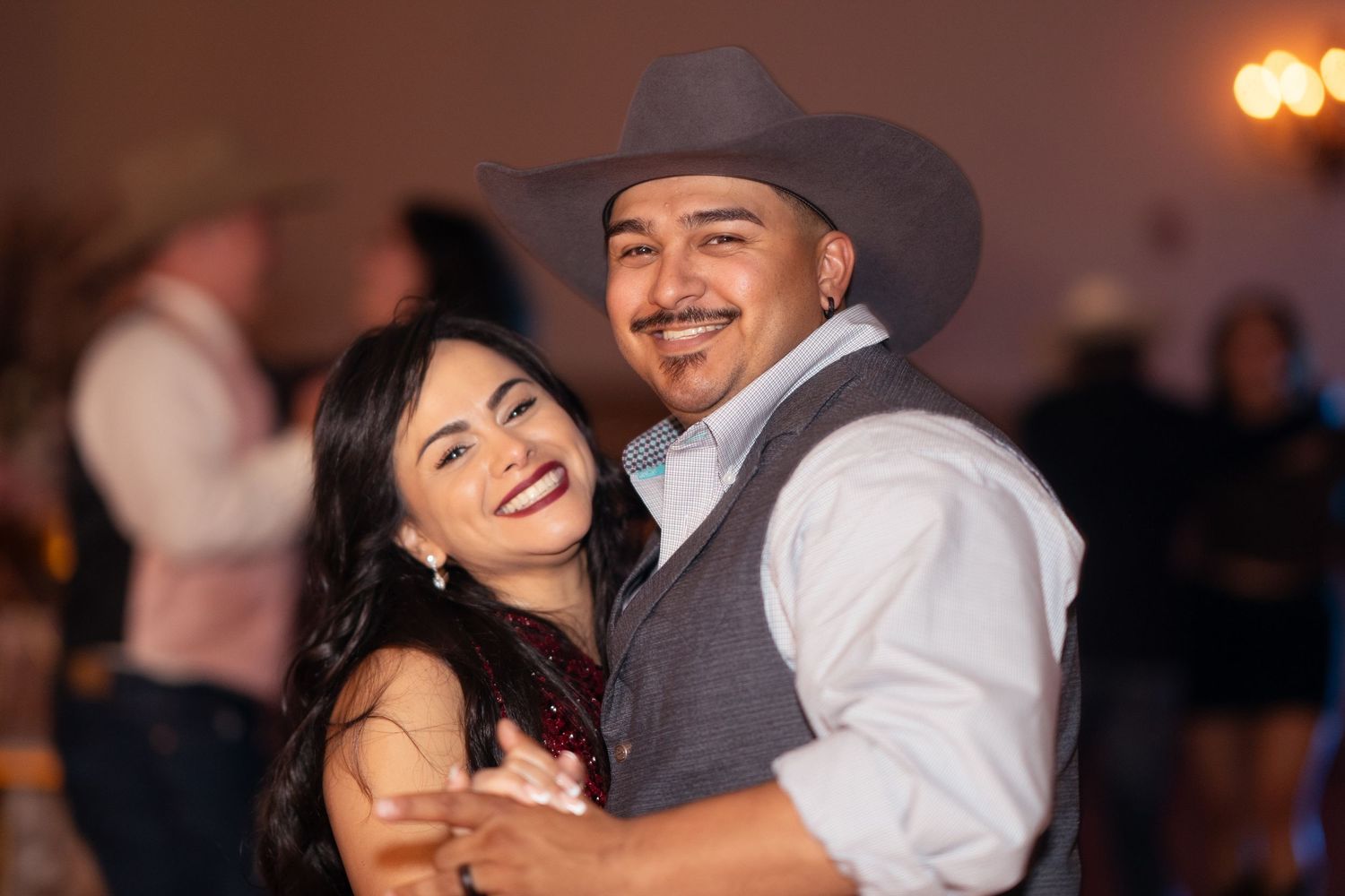 Smiling couple dancing together at a quinceañera celebration in elegant attire.