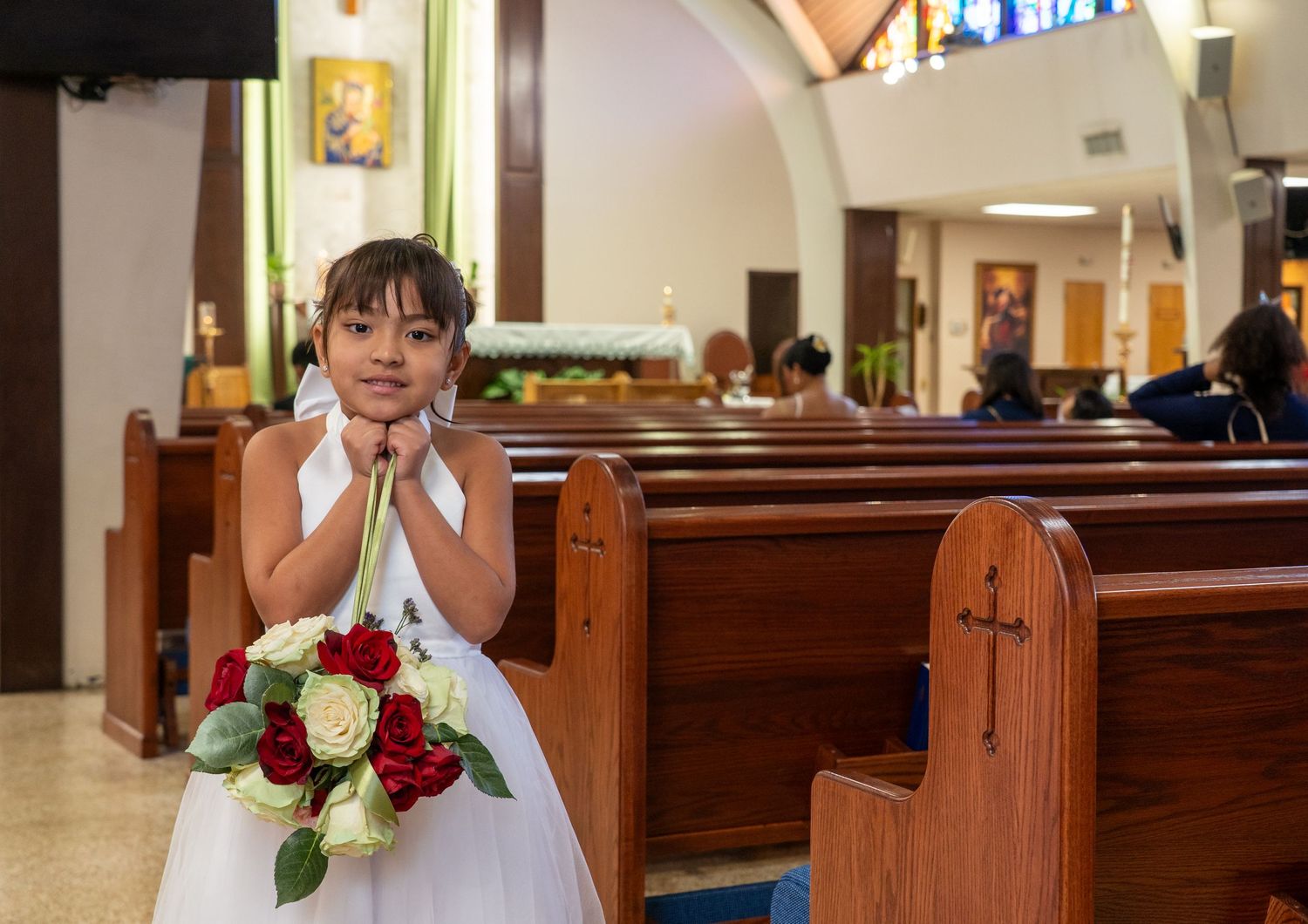 A person in a white dress poses in different positions inside a church with wooden pews and stained glass windows.