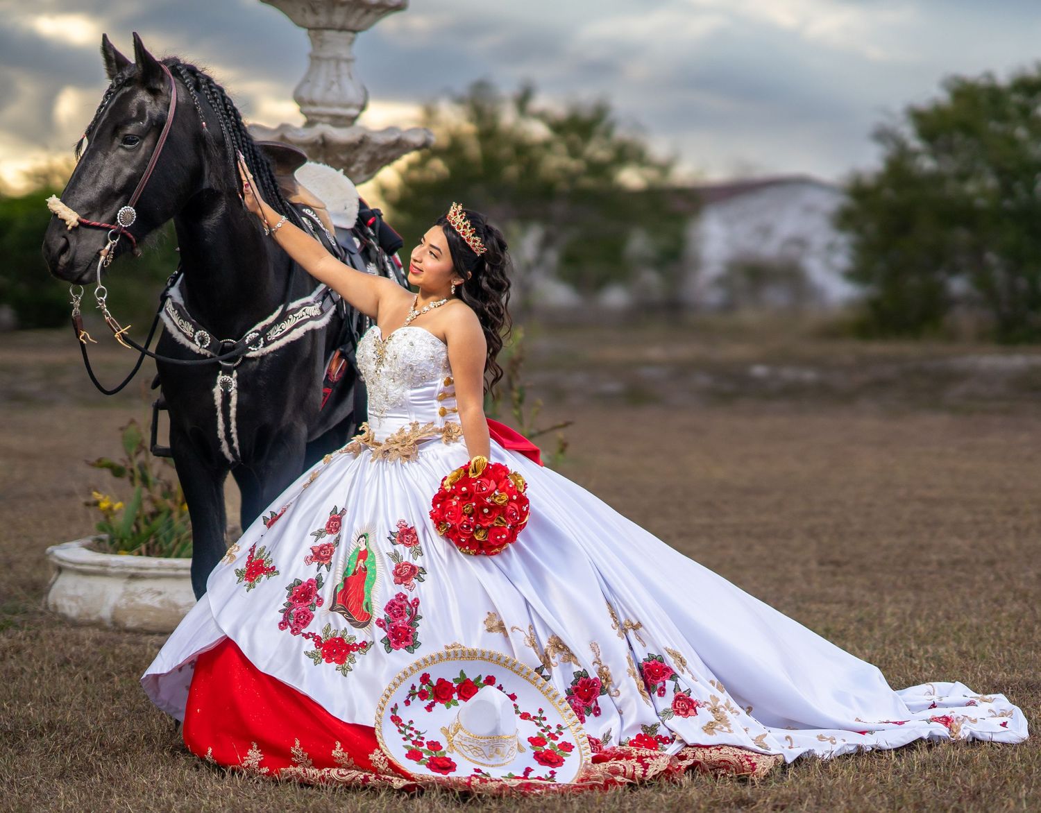 A stunning white and red dress spreads across the ground during an equestrian photoshoot.