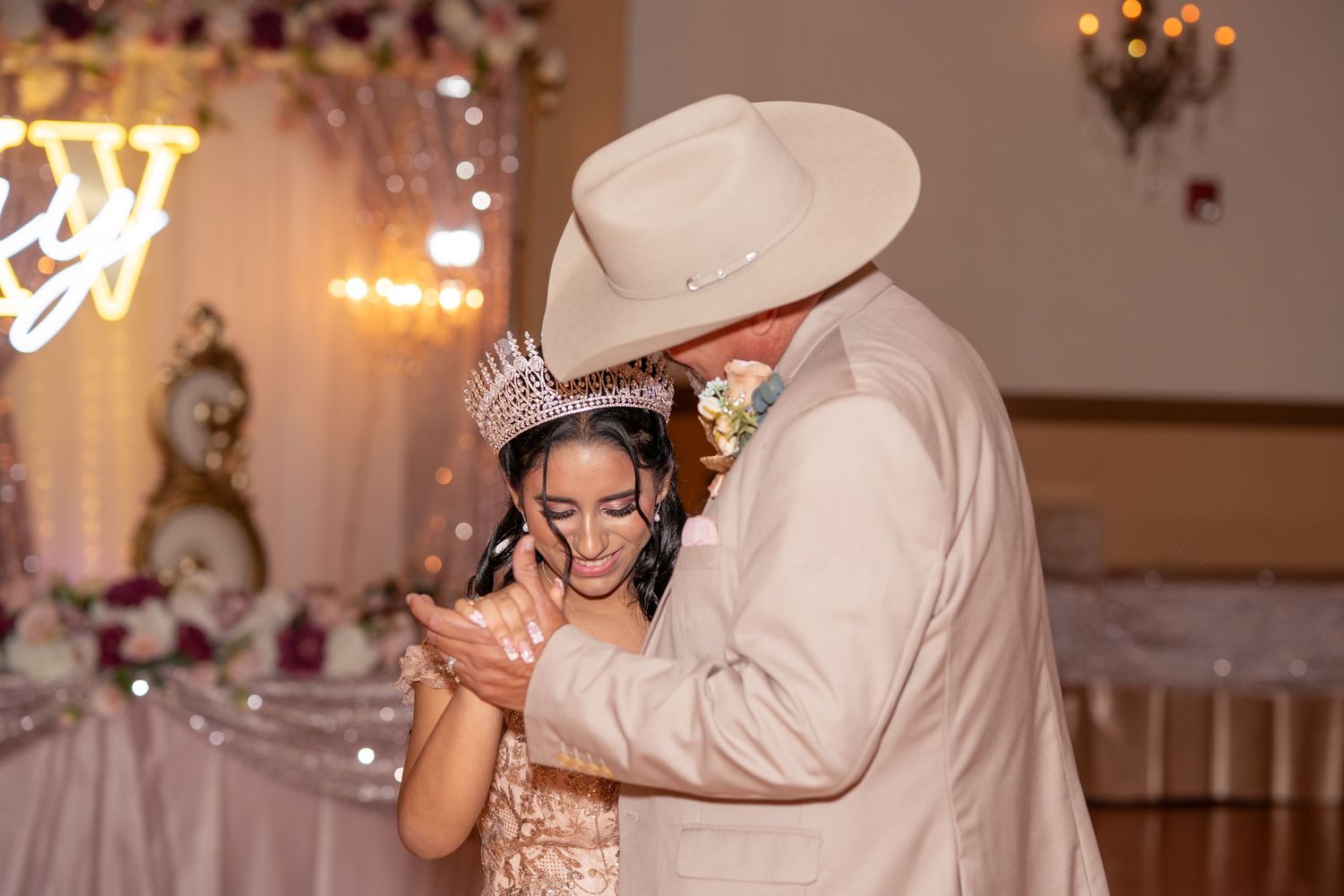 Father shares an emotional dance with his daughter in a gold quinceañera gown and tiara at her celebration.