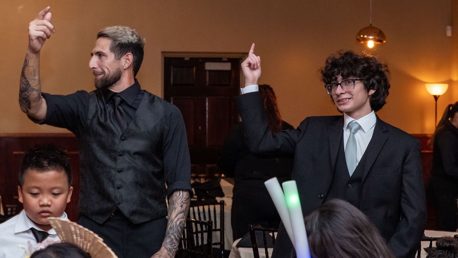 Wedding reception guests dancing and celebrating in a warmly lit venue.