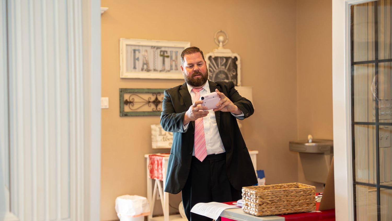 Man in suit using tablet device indoors near decorated table in elegant room setting.
