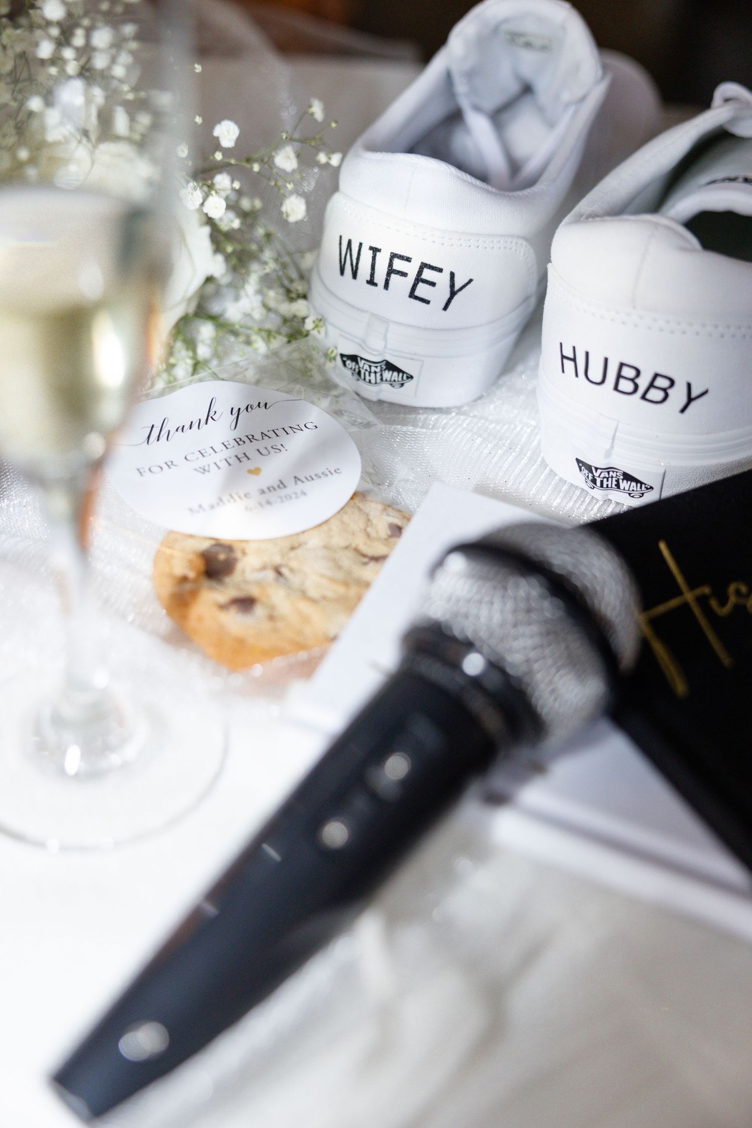 Personalized wedding shoes labeled 'Wifey' and 'Hubby' with champagne and microphone in elegant setting.