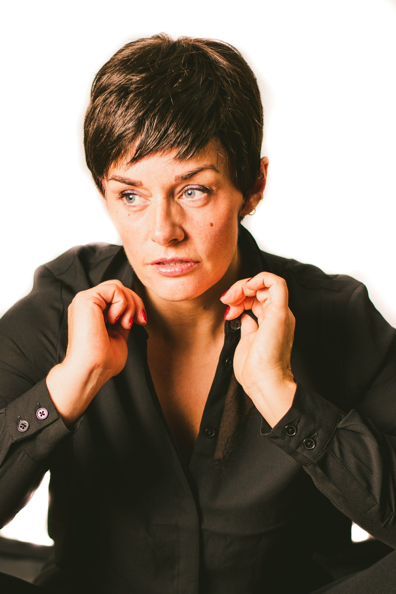 Studio portrait of someone in a black shirt with short dark hair against light background.
