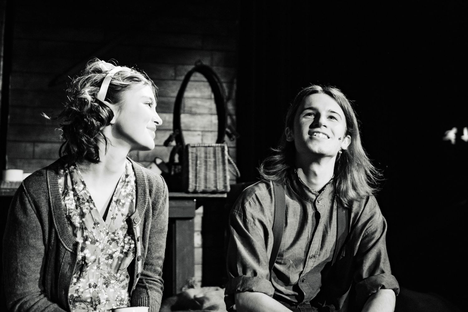 Black and white theatrical scene capturing performers in emotional moment on stage.