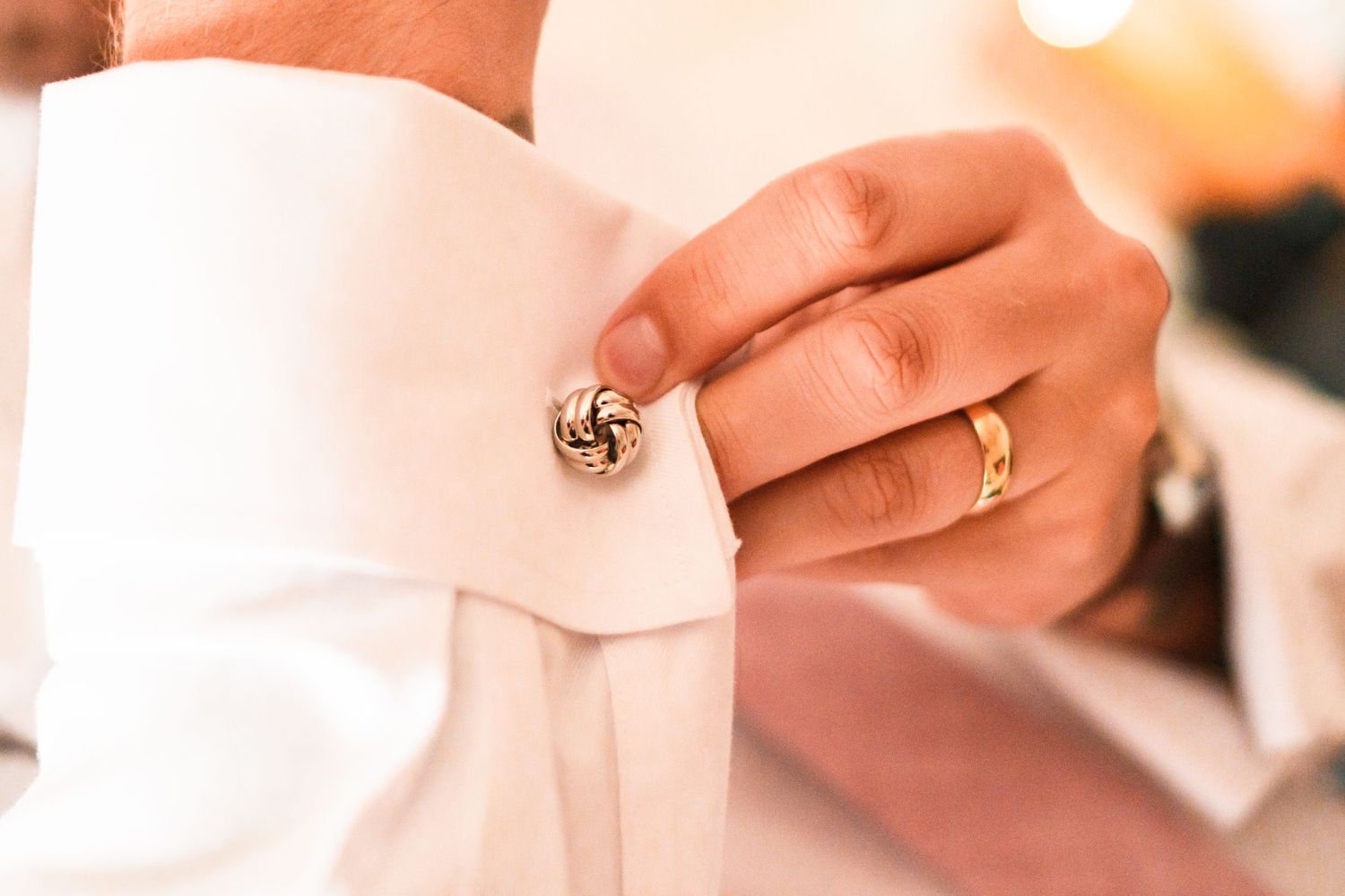 Close-up of decorative knot cufflink on white dress shirt sleeve.