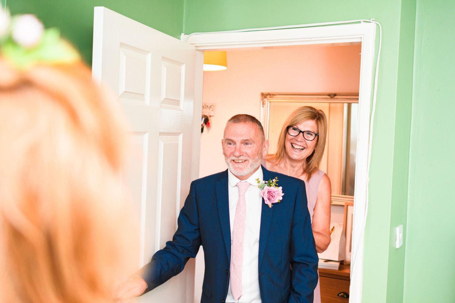 A wedding first look moment captured in a doorway with people sharing a joyful emotional reaction.