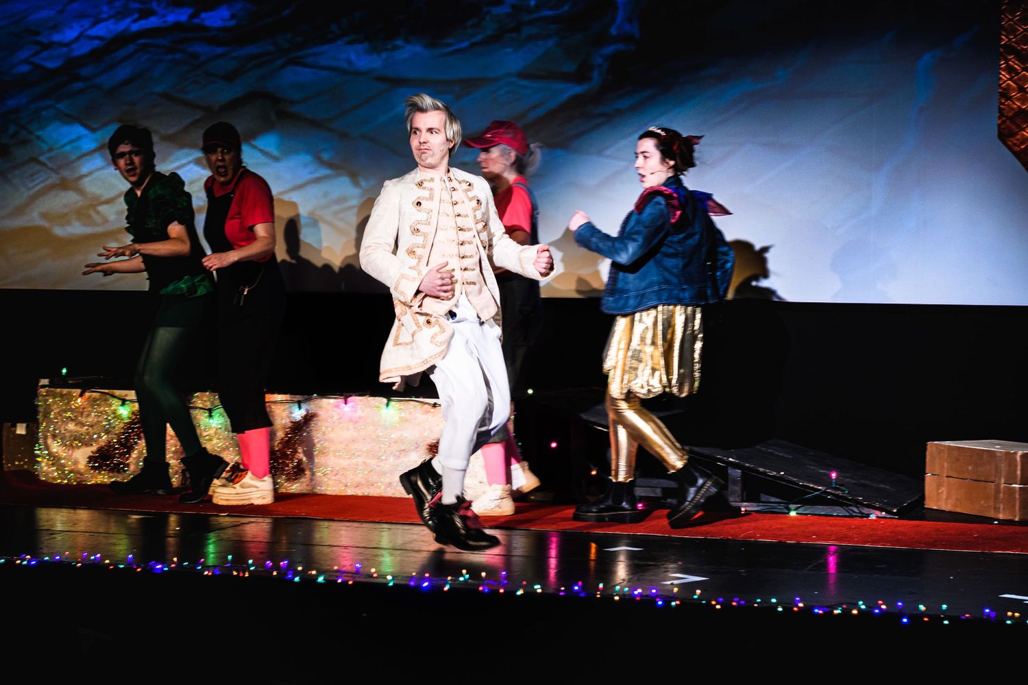 A performer in white costume dances on stage with colorful lighting and decorations.