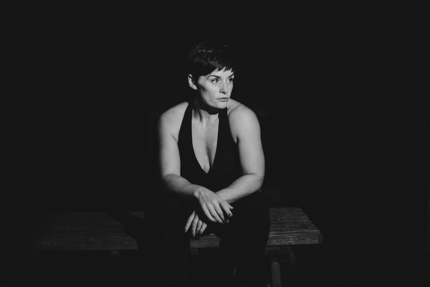 Dramatic black and white portrait of someone in formal attire seated on a bench.