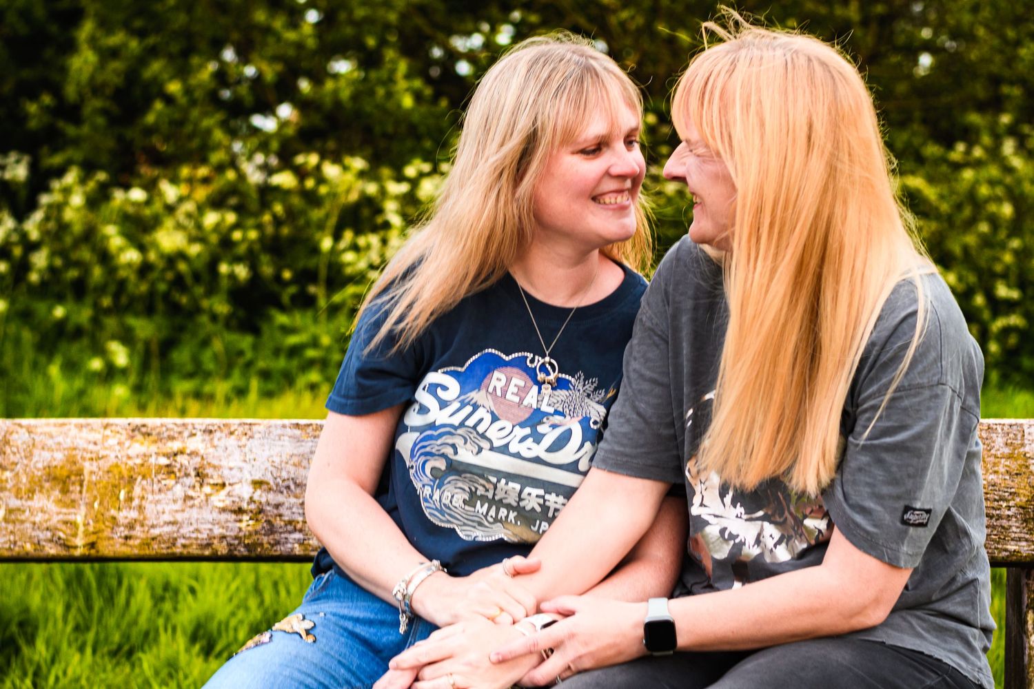 Two people sitting together on a wooden bench sharing a tender moment outdoors.