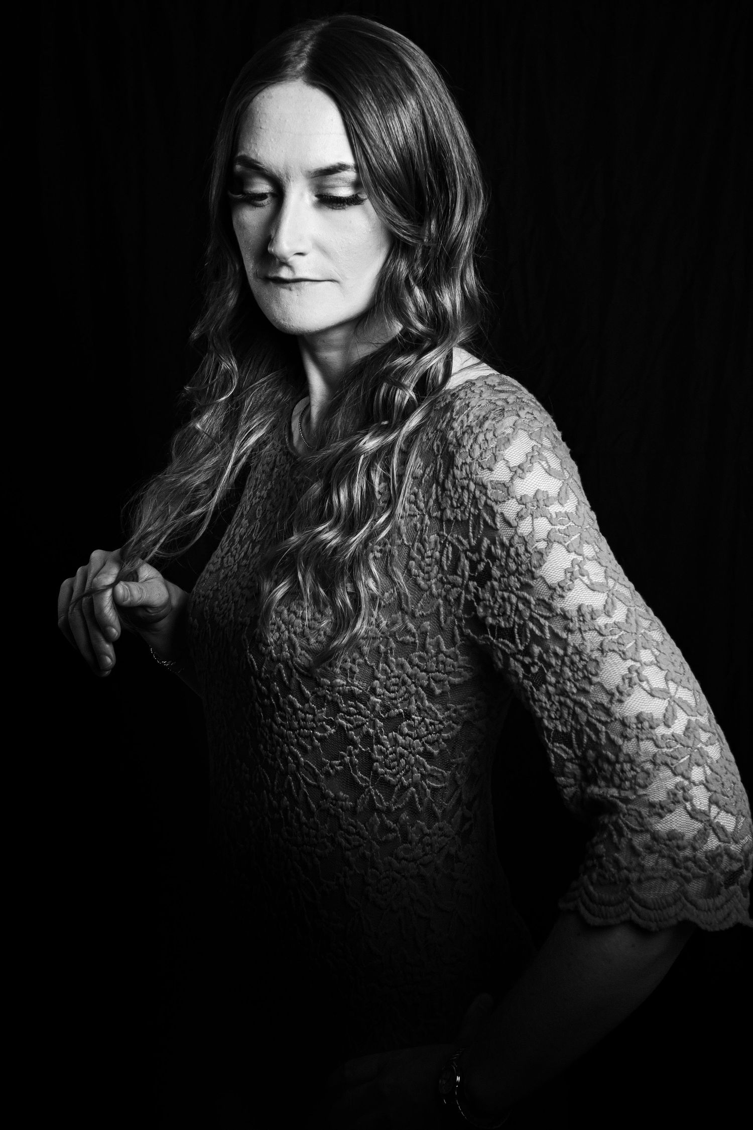 Black and white artistic portrait showing textured lace dress and styled waves.