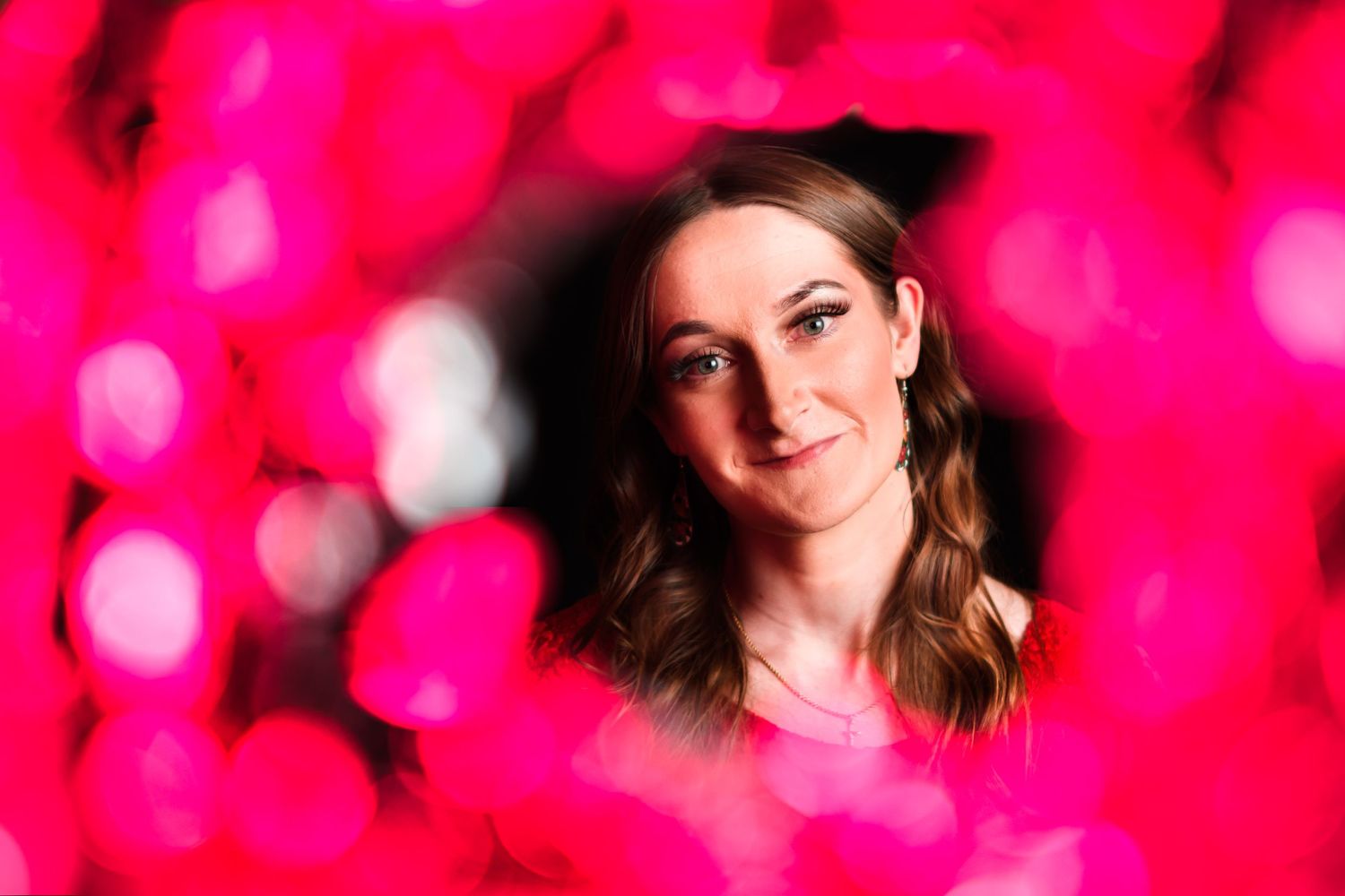 Portrait with soft pink bokeh lighting effects creating a dreamy atmosphere.