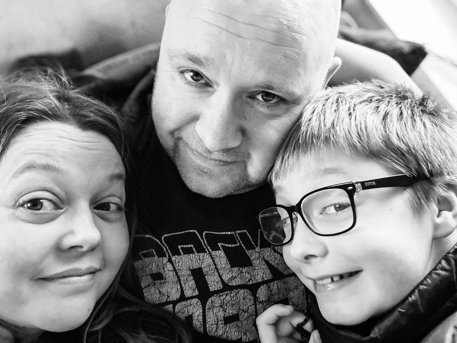 A casual black and white selfie portrait showing a close-knit family moment.