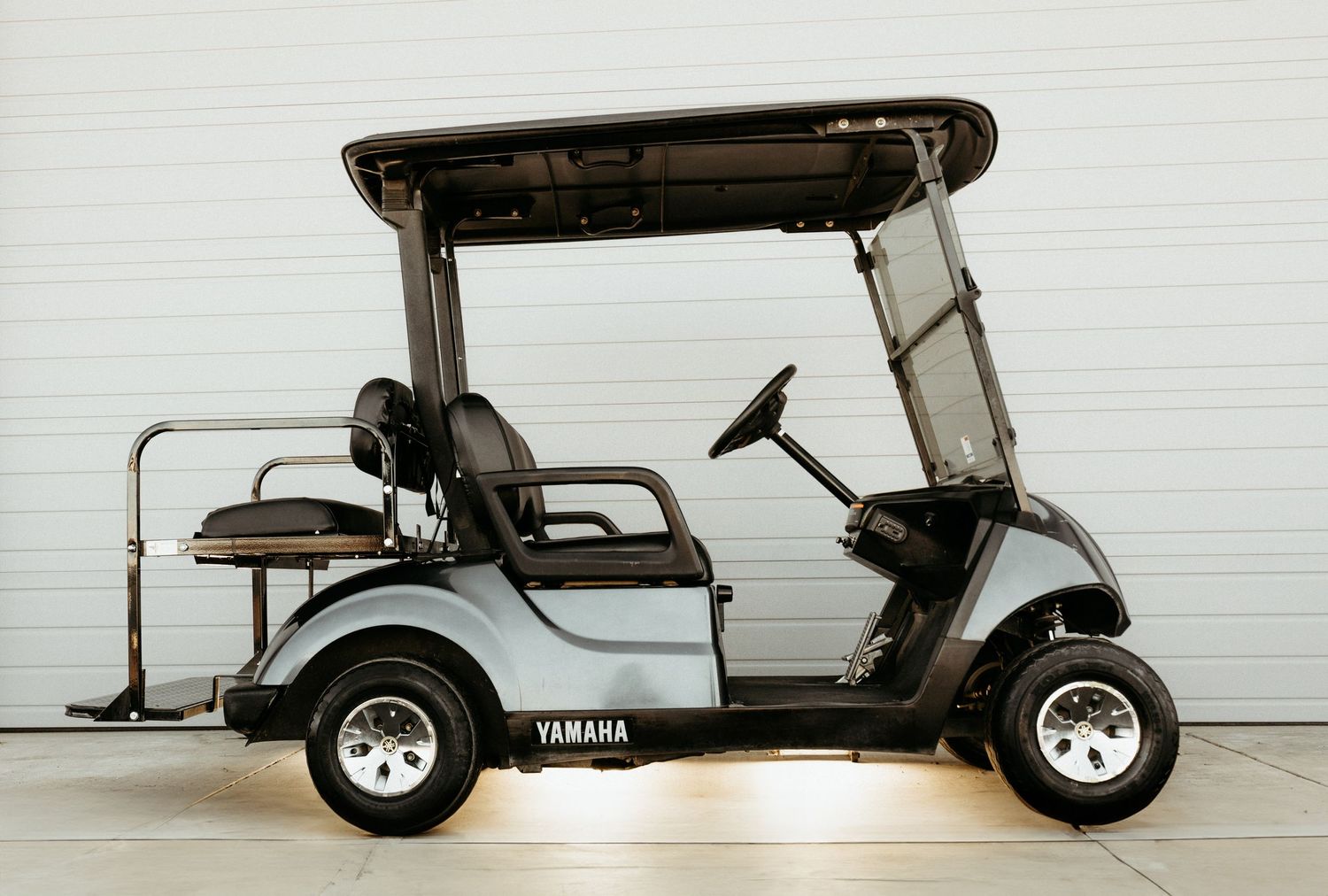 A white Yamaha golf cart with canopy parked against a light colored wall.