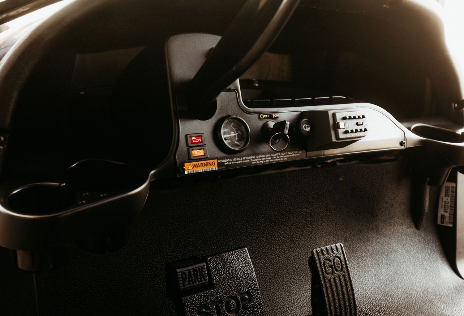 Close-up view of automotive pedals and black interior trim showing a cruise control system interface.