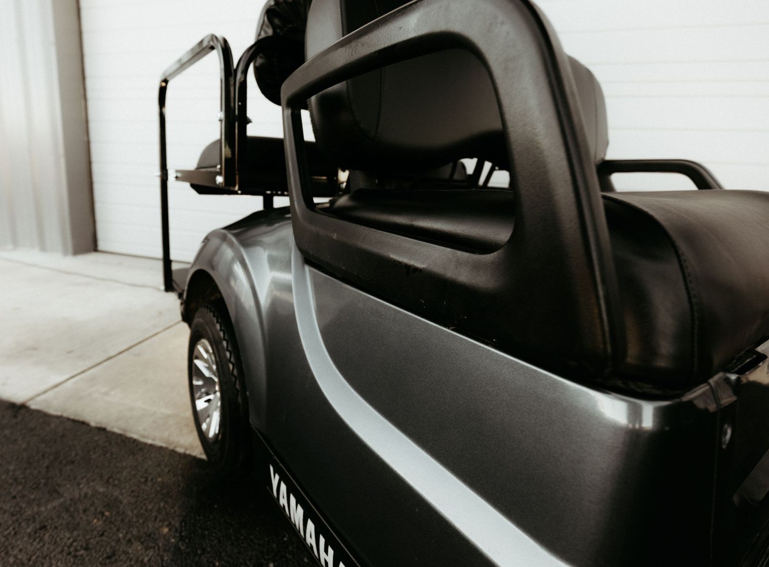 Close-up view of a gray golf cart showing the side panel and passenger area details.