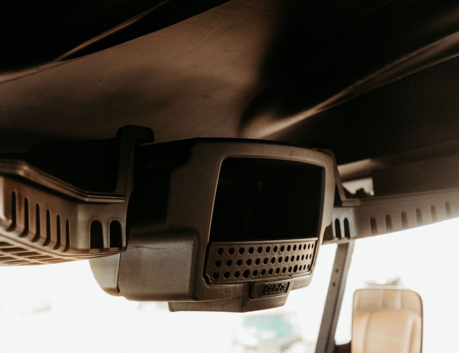 Close-up view of a car's rearview mirror camera system mounted on the interior ceiling in sepia tone.